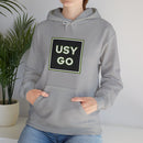 Person wearing a Heavy Blend Hoodie Gildan 18500 Unisex Jersey with big USYGO logo on the front. Made from 50% Cotton 50% Polyester in Sport Grey. Pouch pocket and the tear-away label make for a highly comfortable, scratch-free wearing.