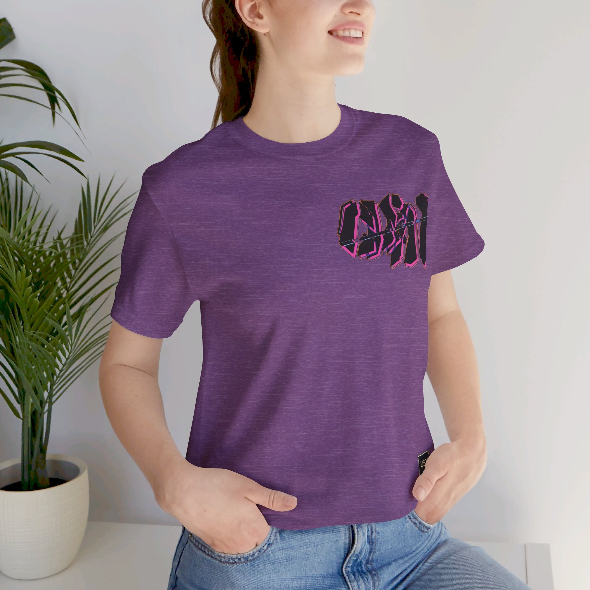 Person wearing Bella+Canvas 3001 Unisex Jersey Short Sleeve Tee with Graffiti Clean design by @johnnygraff31 on the chest left side. Made from lightweight 100% Airlume combed and ring-spun cotton in Heather Purple, ideal for active and leisure wear