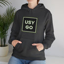 Person wearing a Heavy Blend Hoodie Gildan 18500 Unisex Jersey with big USYGO logo on the front. Made from 50% Cotton 50% Polyester in Dark Heather. Pouch pocket and the tear-away label make for a highly comfortable, scratch-free wearing.